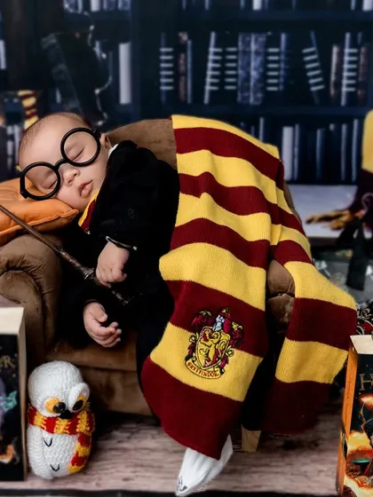 A final shot of the magical setup, showing the baby surrounded by books and props, ready for his first year at Hogwarts.