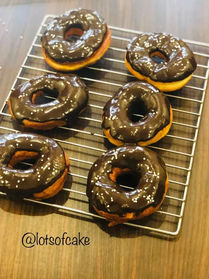 Go nuts for donuts! A batch of my homemade donuts cooling on a wire rack after being dipped in a rich chocolate glaze and finished with sprinkles.