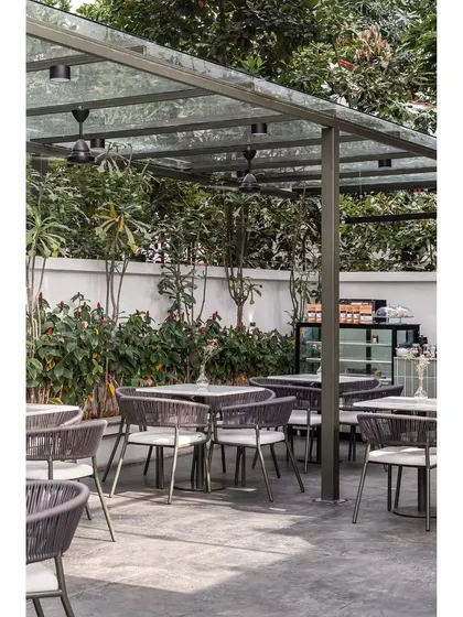 Another perspective of the outdoor seating, showing the simple yet sophisticated olive green metal and grey rope furniture. The design creates a tranquil escape from the urban environment.
