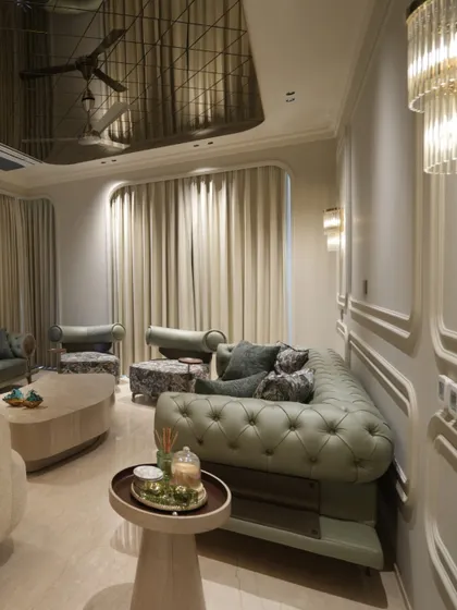 A corner view of the living room, showing the rich texture of the olive green tufted sofa. The floral accent chairs and cushions add another layer of pattern and visual interest to the space.