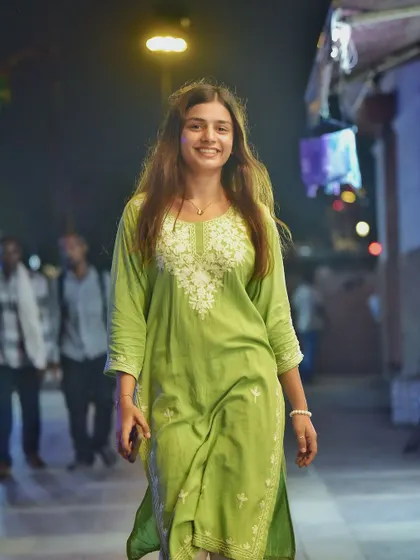 A full-length walking shot that captures the atmosphere of the bustling night market. This lifestyle portrait tells a story of exploring the city after dark.