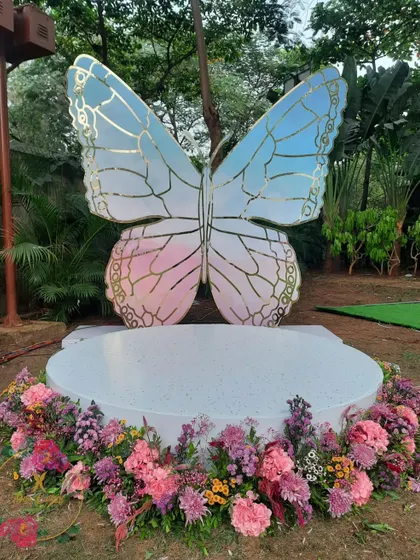 The butterfly photo booth during the day, with its iridescent colors and surrounding floral base, creating a beautiful focal point.