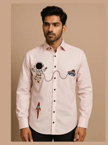 A full view of the astronaut-themed shirt, showing the playful arrangement of the embroidered astronaut, UFO, and rocket motifs.
