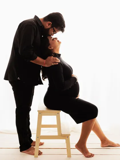 A classic pose from a minimalist maternity session. The father-to-be's gentle kiss on his partner's forehead speaks volumes of his love and support.
