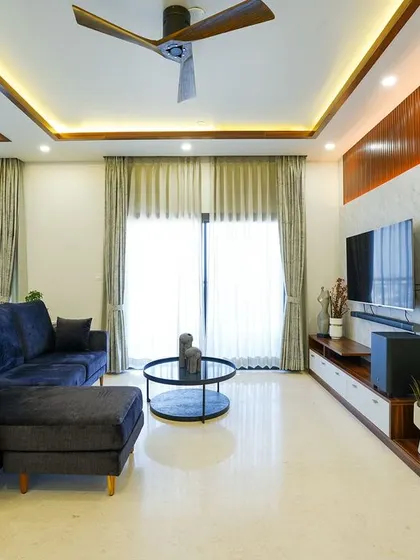 This modern living room combines a plush navy sofa with a stylish TV unit featuring a marble-effect back panel and warm wood fluting, creating a balanced and sophisticated entertainment area.