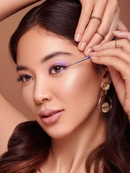 A close-up demonstrating the precision of an eyeliner brush. The model's eye is perfectly lined with a vibrant purple, showcasing the brush's fine tip and control. This shot is ideal for highlighting the technical capabilities of a makeup tool.