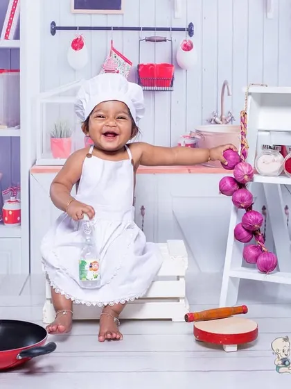 This little chef is having the time of her life in our kitchen set! Her huge smile and the fun props, like the pan and rolling pin, make this a truly joyful and memorable shot.