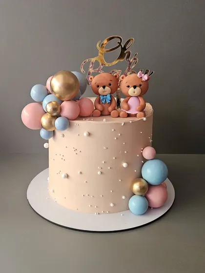 A pretty teddy bear cake for a baby shower. This chocolate truffle cake features adorable "he or she" teddy bear toppers and a cascade of pink and blue chocolate spheres.