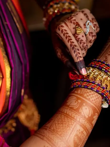 Here, the bride adjusts her bangles, giving a glimpse of the detailed band work on her wrist and the delicate leafy vines on the back of her hand.