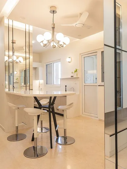 This image shows the interplay between different functional zones. The breakfast bar provides a casual dining spot, while the mirrored partition cleverly separates the space without closing it off.