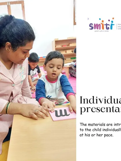 An individual presentation of the sandpaper letters, where a teacher introduces the phonetic sound of 'm'. This one-on-one guidance ensures each child receives personalized attention and masters concepts at their own pace.