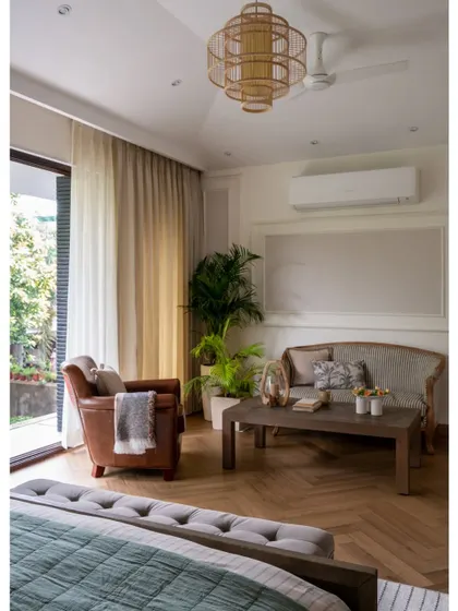 This image from a feature showcases the sitting area in the master bedroom. The blend of a classic settee, a leather armchair, and herringbone floors creates a timeless and sophisticated retreat.