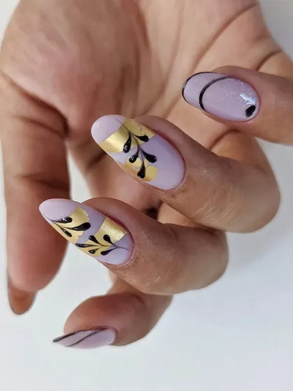 An elegant design on oval extensions, featuring black swirls and gold foil accents on a soft lavender base.