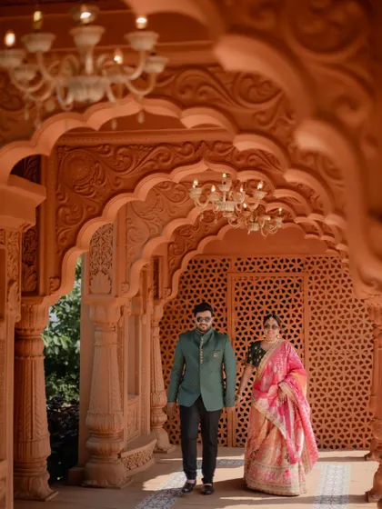 The couple walks through an ornate corridor, with the groom looking lovingly at his bride. A candid moment from their royal-themed pre-wedding shoot.