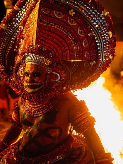 Close-up and action shots of the Kandanar Kelan Theyyam, focusing on the detailed costume, expressive mask, and the raw power of the fire performance.