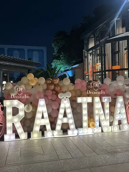 The "RAATNA" marquee letters glowing at night, creating a stunning focal point in the outdoor party area.