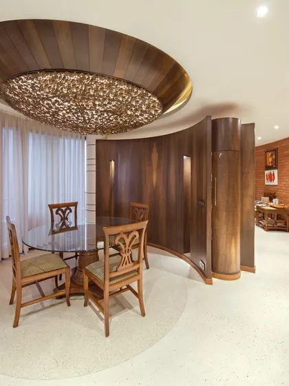 The dining area in the Outré House, where a stunning hemispherical ceiling detail with a custom 'Champa' lamp creates an intimate and dramatic focal point.