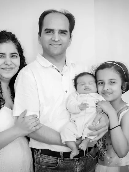 A complete family portrait in black and white, with parents, a proud big sister, and the sleeping newborn.