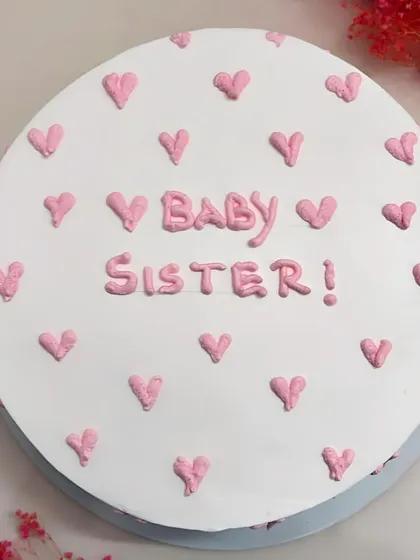 A top-down view of the 'Baby Sister' cake, showing the pattern of little pink hearts.