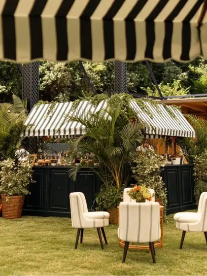 A chic lounge area set up on the grass, featuring striped armchairs and a stylish bar cart. This inviting corner provides a comfortable and picturesque spot for guests to relax.