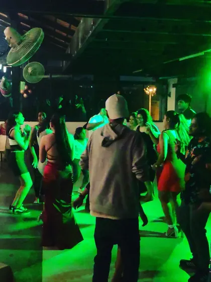 A view from behind a guest, looking onto the green-lit dance floor.