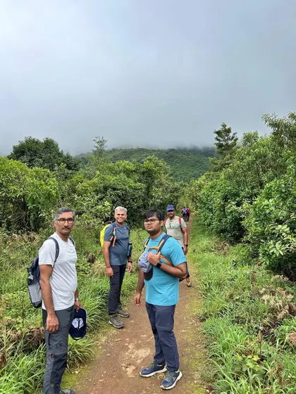 Posing on the trail of the Thadiyandamol trek, with the misty mountains of Coorg in the background.