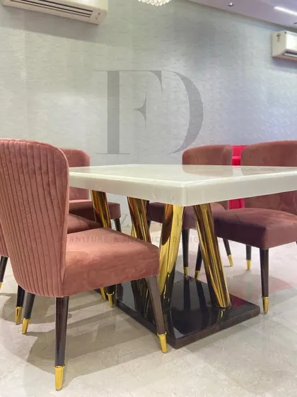 A detailed shot of the dining table's base, which features a combination of dark wood and angled, polished gold legs. This showcases our commitment to creating unique and sculptural furniture pieces.