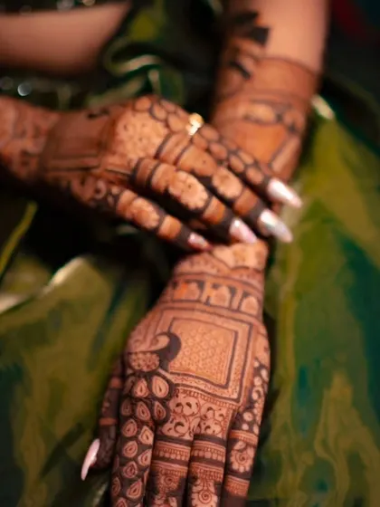 A close-up shot focusing on the rich detail and fine lines of our bridal henna work. Notice the clean execution of the peacock and checkerboard patterns on the hand.