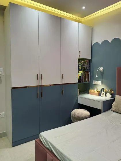 The two-tone wardrobe design provides ample storage while the cloud-shaped wall paint adds a whimsical touch to this child's bedroom.