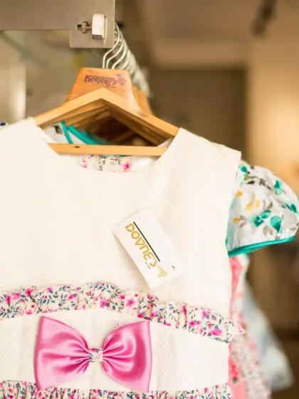 A close-up of the white and pink floral dress, showing the "Doyne's" tag and the quality craftsmanship.