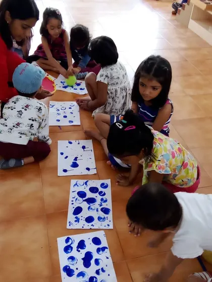 Children engage in splatter painting during our Holi celebration. This energetic art activity is all about the process and the joy of seeing colors mix and fly.