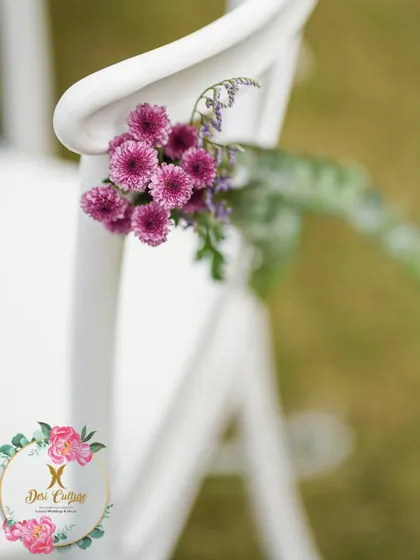 A cluster of purple chrysanthemums tied to a chair, showing how even small floral details can be coordinated with the event's color scheme.