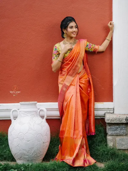 A full-length shot of Ragini in the orange ikat saree, showcasing its beautiful drape and rich color.