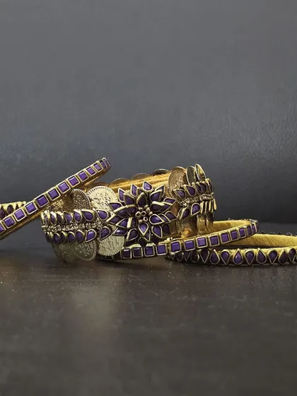 The complete purple bangle set laid out, showing the central floral piece and accompanying bangles.