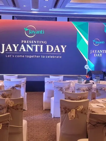 The final setup for the "Jayanti Day" corporate celebration at Shangri-La Bengaluru, featuring a clean stage design and elegant table arrangements.