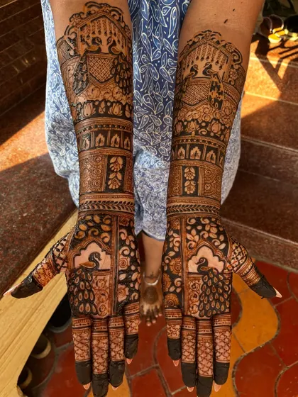A stunning engagement mehendi with full coverage. The design is packed with traditional elements like peacocks and architectural domes, perfect for a grand celebration.