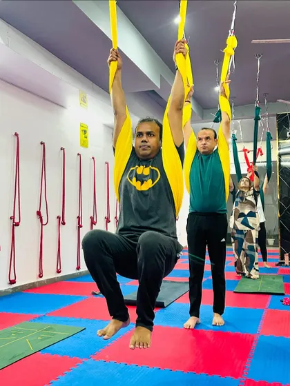 Aerial yoga is not just for the flexible; it's a great way to build strength. Here, students use the hammocks for suspended pull-ups, engaging their core and upper body.
