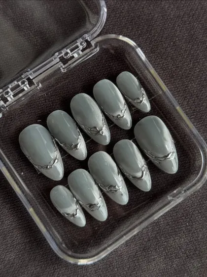 For those who love a modern, edgy vibe. This set features a muted sage green base with raised, liquid-like silver chrome accents. The 3D detailing gives these custom press-on nails a unique texture that looks and feels like wearable art.