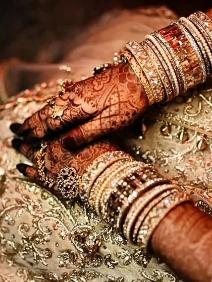 A beautiful, soft-focus shot of the bride's hands, highlighting the rich color of the henna stain.