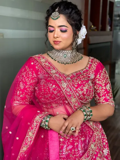 A soft, romantic reception look with a focus on pink tones for the eyes and a classic updo with a white flower.