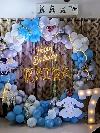 A dreamy Cinnamoroll themed balloon ring for a 7th birthday. The setup uses a lovely blue, white, and grey color palette with character cutouts and a light-up marquee number.