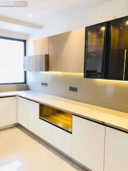 This modern kitchen design uses a mix of white lower cabinets and wood-textured fluted panels on the upper cabinets for a warm, contemporary aesthetic.