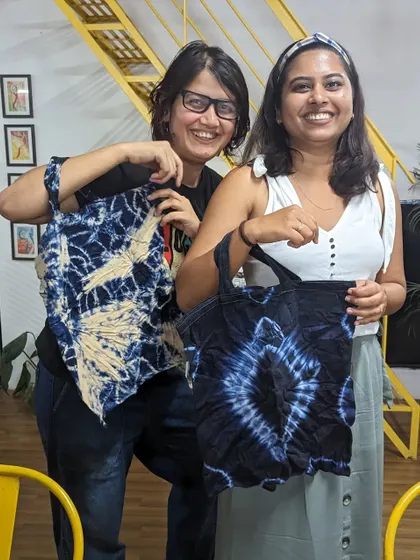 Two friends showing off the tote bags they tie-dyed at our workshop. A perfect, personalized accessory!