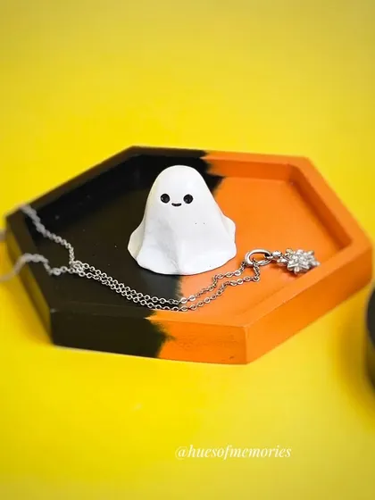 A spooky and cute trinket tray for your Halloween decor. This hexagonal tray is split between black and orange and features an adorable little ghost figurine.