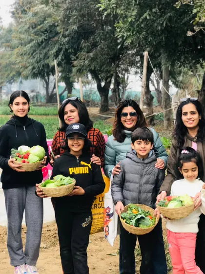 A happy family shows off their impressive harvest. With baskets full of different vegetables, they've had a productive and fun day on the farm.