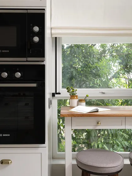 We broke down a wall to create a French door leading to a balcony, flooding the kitchen with natural light. A small prep table by the window doubles as a perfect spot for a morning cup of coffee.