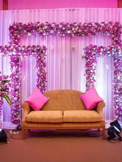 A vibrant stage setup with a frame of purple and pink flowers against a white curtain backdrop. This is a great option for a lively corporate party or team celebration.