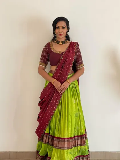 A graceful standing pose in the lime green and maroon half saree. This is a popular color combination that looks great in photos.