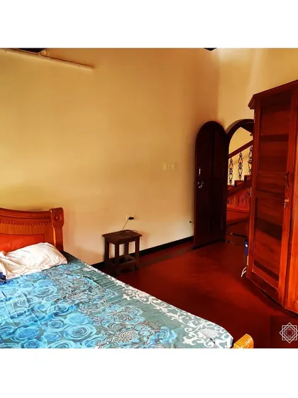 A simple and elegant bedroom in the Udupi project. The warmth of the reclaimed wood furniture and the red oxide floor creates a serene and restful atmosphere.