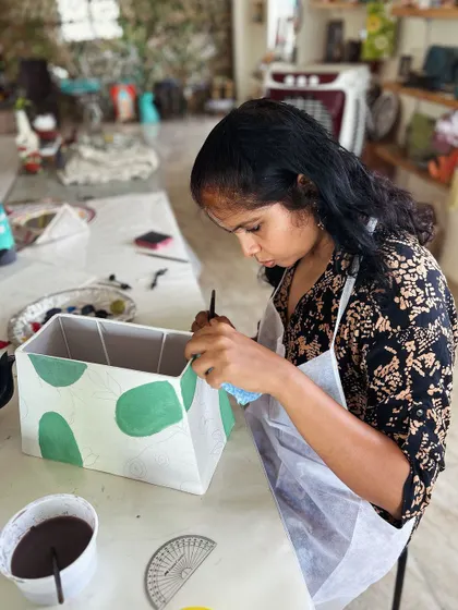 A participant painting a custom design on a lampshade.